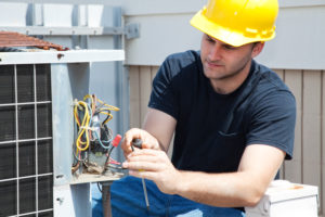 A technician repairing a rooftop condenser unit